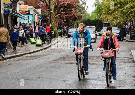 Ein paar Radfahrer auf "Boris Bikes" Talfahrt Queensway in Bayswater, London. Stockfoto