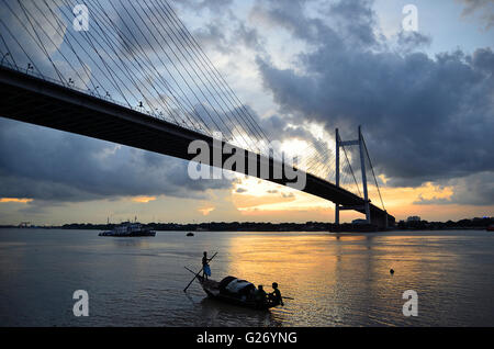 Regen Wolken schweben über zweite Hooghly Brücke bei Sonnenuntergang mit Land Angeln Boote schwimmen im Fluss unten, Kolkata, Westbengalen Stockfoto