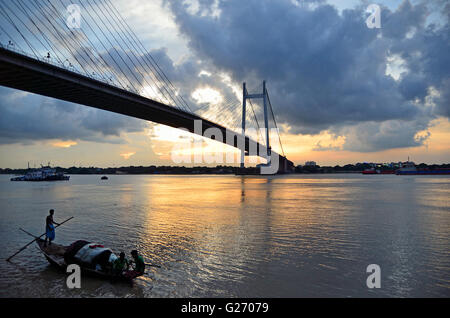 Regen Wolken schweben über zweite Hooghly Brücke bei Sonnenuntergang mit Land Angeln Boote schwimmen im Fluss unten, Kolkata, Westbengalen Stockfoto
