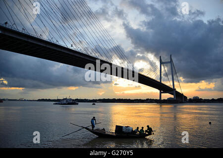 Regen Wolken schweben über zweite Hooghly Brücke bei Sonnenuntergang mit Land Angeln Boote schwimmen im Fluss unten, Kolkata, Westbengalen Stockfoto