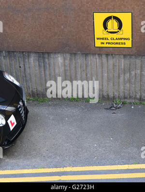 Illegales parken, schwarzen Auto parkte auf doppelte gelbe Linien neben ein Warnhinweis über Rad spannen. 24. Mai 2016 Stockfoto