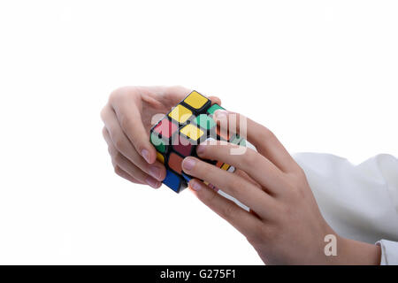 Kind hält einen Zauberwürfel in der Hand auf einem weißen Hintergrund Stockfoto