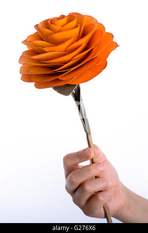 Hand mit einer Rose aus Holz auf einem weißen Hintergrund Stockfoto