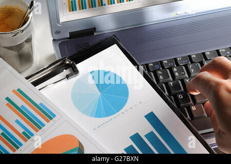 Geschäftsmann, einen Laptop eingeben und überprüfen einige Diagramme im Büro Stockfoto