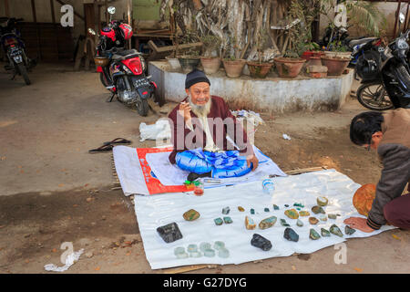 Bärtige Verkäufer mit Anzeige der Rohschnitt Stücke aus Jade auf Verkauf am Straßenrand auf dem Jademarkt, Mandalay, Myanmar (Burma) Stockfoto