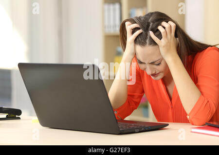 Traurig und verzweifelt Freiberufler weiblich auf Linie mit einem Laptop mit ihren Händen auf dem Kopf sitzen in einem Büro oder zu Hause arbeiten Stockfoto