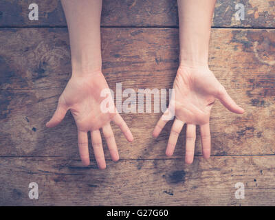 Eine Frau, die ihre Handflächen an einem Holztisch hautnah Stockfoto