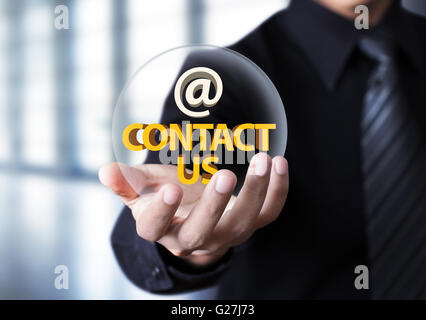 Kontaktieren Sie uns-Symbol in der Geschäftsmann Hand, Geschäftsmann mit 'Kontakt' Text in Crystal ball Stockfoto