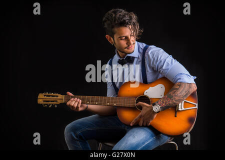 Porträt von Hipster Gitarre vor schwarzem Hintergrund, im Studio gedreht Stockfoto