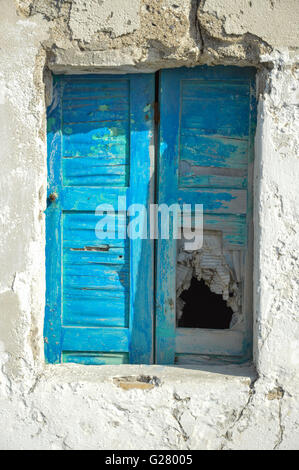 eine alte beschädigt griechische Fenster in einem schlechten Zustand mit blauen Farbe auf die geschlossenen Fensterläden in einer weißen gerenderten Wand Griechenland läuten Stockfoto