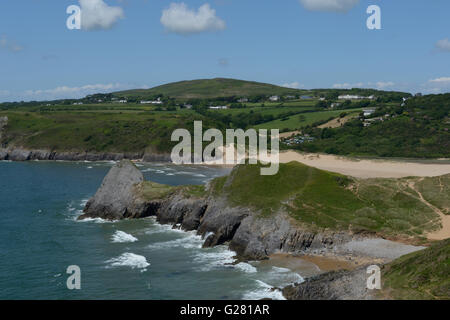 Sandstrände gesäumt mit Surf und grünen Wiesen umgeben Three Cliffs Bay in Wales mit Cefyn Bryn am Horizont.  Gower Ausflugsort. Stockfoto