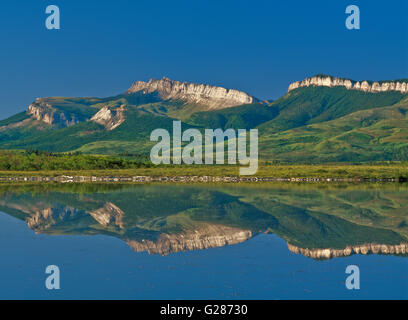 Mauerwerks Riff entlang der felsigen Berg spiegelt sich in einem Sumpfgebiet in der Nähe von Dupuyer, montana Stockfoto