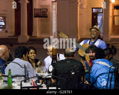 Traditionelle kubanische Musiker Gitarrist unterhält Menschen trinken in einer Bar im Freien auf der Plaza Vieja, Havanna, Kuba. Stockfoto