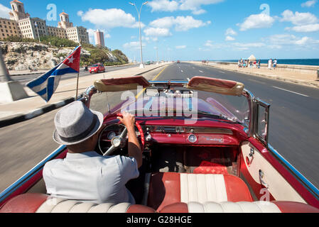 Eine kubanische Taxifahrer fahren his1955 Pontiac Star Chief Cabrio entlang des Malecón in Havanna, Kuba. Stockfoto