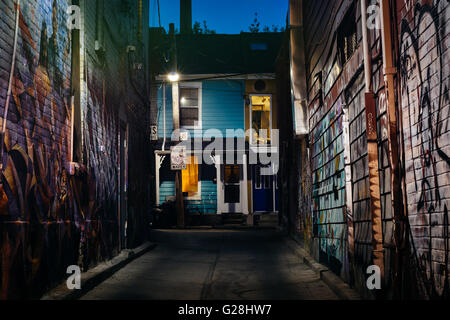 Graffiti in einer Gasse und ein blaues Haus in der Nacht in Kensington Market, in Toronto, Ontario. Stockfoto