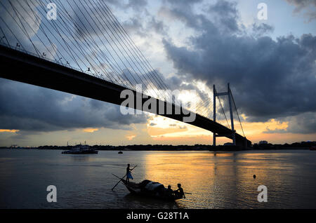 Regen Wolken schweben über zweite Hooghly Brücke bei Sonnenuntergang mit Land Angeln Boote schwimmen im Fluss unten, Kolkata, Westbengalen Stockfoto