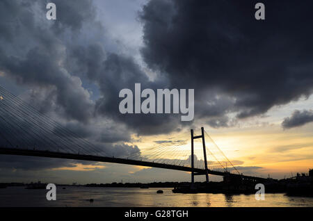 Regen Wolken schweben über zweite Hooghly Brücke bei Sonnenuntergang mit Land Angeln Boote schwimmen im Fluss unten, Kolkata, Westbengalen Stockfoto