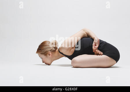 Attraktive junge Japanerin tragen schwarze Hosen und Tank-Top praktizieren Yoga auf weißem Hintergrund Stockfoto