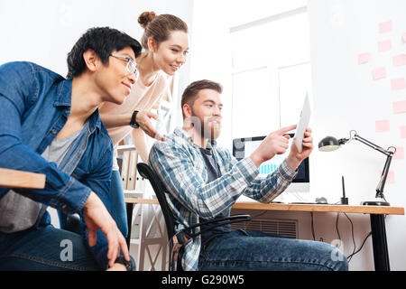 Drei glückliche junge Geschäftsleute arbeiten und mit tablet im Büro Stockfoto