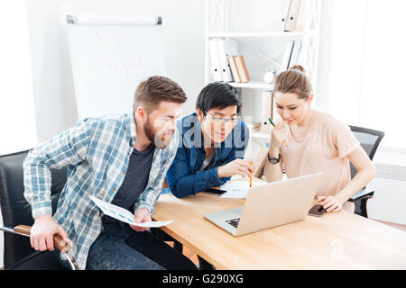 Drei konzentriert junge Geschäftsleute, die gemeinsam mit Laptop im Büro Stockfoto