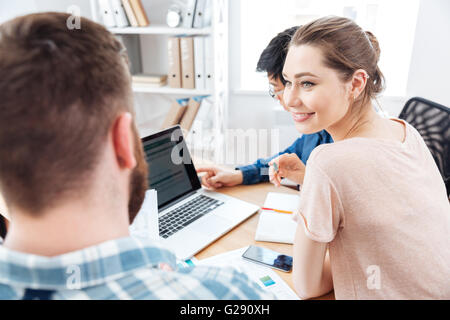 Glücklich attraktive junge Frau sitzen und arbeiten mit zwei Jungunternehmer im Büro Stockfoto