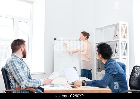 Lächelnde schöne junge Frau, Präsentation für ihre Kollegen auf der Sitzung im Büro Stockfoto