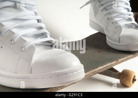 Mann in sauberen weißen Trainer machen Tricks auf einem alten skateboard Stockfoto