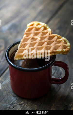 herzförmige Waffeln und Kaffee am Tisch in der Nähe von Stockfoto
