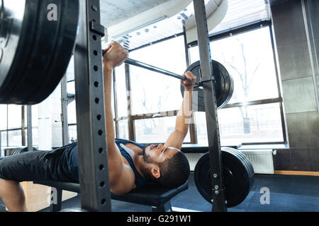 Mann Fitnesstraining mit Langhantel in Turnhalle Stockfoto