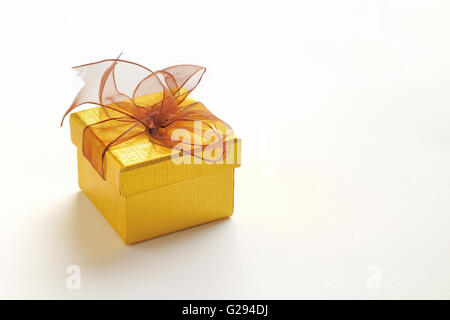 Dekorative goldene Geschenkverpackung mit braunen Krawatte und geriebenem Textur. Erhöhten Blick. Weiß isoliert Hintergrund. Stockfoto