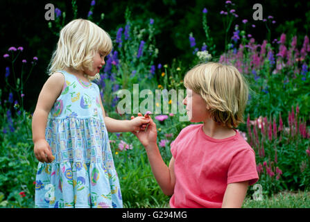 Zwei Mädchen (Schwestern) in einem Garten mit Blick auf Blumen, Blumen in Missouri Stockfoto