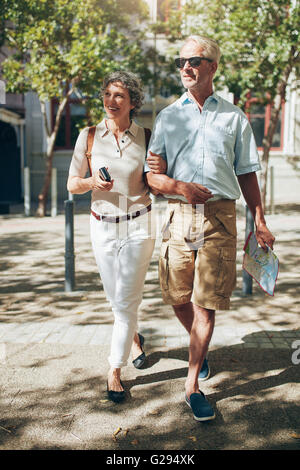 Älteres Paar zu Fuß durch die Stadt im Besitz einer Karte. Glücklich senior Mann und Frau in den Urlaub. Stockfoto
