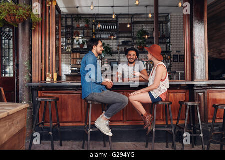 Gruppe von Jugendlichen in einem Café sitzen und reden. Junge Männer und Frauen treffen im Café-Tisch. Stockfoto