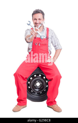 Kfz-Mechaniker hält gekreuzt Schraubenschlüssel oder Schraubenschlüssel auf Rad sitzen Stockfoto