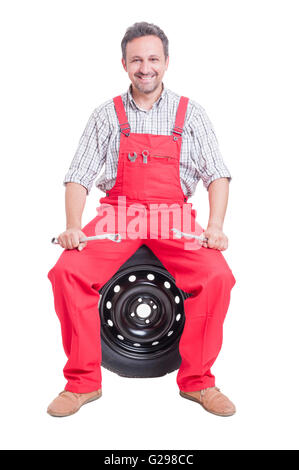 Freundliche Mechaniker auf Auto-Rad sitzen und Lächeln, isoliert auf weiss Stockfoto