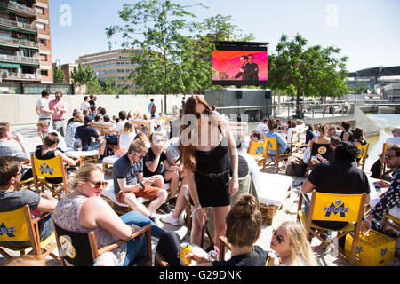 Die Teilnehmer sitzen draußen in der Sonne und beobachten die Vorträge vom Hauptsaal Roots Room auf einer großen Außenwand im OFFF Barcelona im Disseny Hub Museum of Design in Barcelona, Spanien, 26. Mai 2016. Der erste Tag des OFFF-Festivals (Let's Feed the Future) in Barcelona. Dieses Design-Festival ist jetzt sein 16. Jahr. Im Bild: Eine Menschenmenge versammelt sich draußen, um die Präsentationen auf einer Großleinwand anzusehen. Quelle: Rob Watkins/Alamy Live News Stockfoto