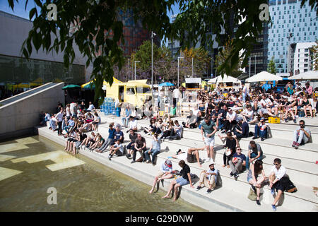 Die Teilnehmer sitzen draußen in der Sonne und beobachten die Vorträge vom Hauptsaal Roots Room auf einer großen Außenwand im OFFF Barcelona im Disseny Hub Museum of Design in Barcelona, Spanien, 26. Mai 2016. Der erste Tag des OFFF-Festivals (Let's Feed the Future) in Barcelona. Dieses Design-Festival ist jetzt sein 16. Jahr. Im Bild: Eine Menschenmenge versammelt sich draußen, um die Präsentationen auf einer Großleinwand anzusehen. Quelle: Rob Watkins/Alamy Live News Stockfoto