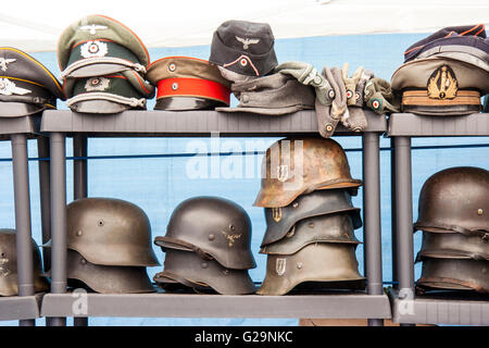 Zwei Racks der Deutschen erster Weltkrieg und Zweiter Weltkrieg Helme, stahlhelm, und die Kappen auf den Anzeigen für Verkauf an den jährlichen Krieg und Frieden zeigen in England. Stockfoto