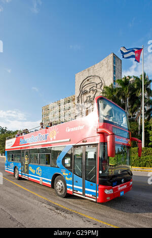 Ein Tourist-Hop on Hop off-Bus am Platz der Revolution am Gebäude des Innenministeriums mit dem Bild von Che Guevara vorbei fahren. Stockfoto