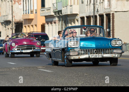 Ein 1958 Pontiac Super Chief (blaues Auto) und eine 1950 Chevrolet Bel Air (lila Auto) Reisen entlang der Malecón in Havanna, Kuba. Stockfoto