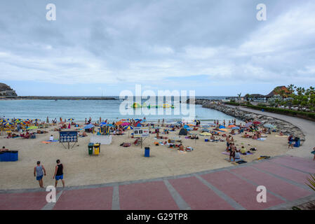 Touristen packen Amadores Strand im Süden von Gran Canaria, trotz bewölktem Himmel Stockfoto