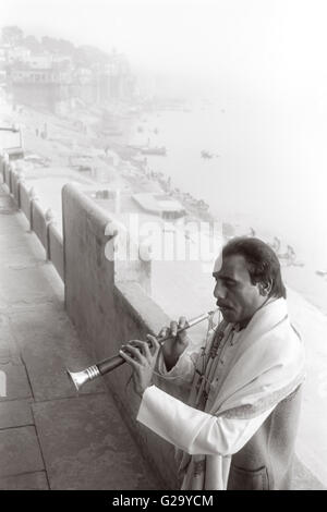 Ein indischer Musiker steht mit dem Rücken zum Fluss Ganges während eine Noth indische Oboe spielen ein Shehnai genannt. Stockfoto
