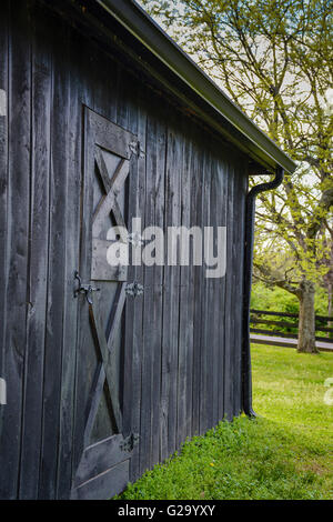 Ein Schmied rustikalen schwarzen hölzernen Stall verwendet für Hufbeschlag und Pflege auf einer Pferdefarm im Frühjahr hat eine nostalgische Atmosphäre Stockfoto