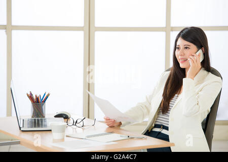 Asiatische Geschäftsfrauen mit Smartphone am Schreibtisch im Büro Stockfoto