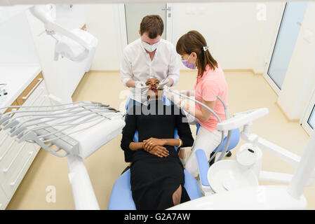 Patientin mit schönen Lächeln, die mündlichen Prüfung in Zahnarztpraxis Stockfoto