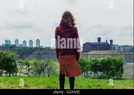 Schuss der Rückansicht einer jungen Frau auf einige Rasen stehen und bewundern die Aussicht auf die Stadt Stockfoto