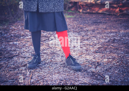 Eine junge Frau trägt seltsame Leggins und steht auf dem frostigen Boden im Wald an einem Wintertag Stockfoto