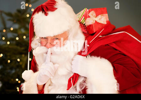 Porträt von Santa Claus mit Finger auf Lippen, Sack über die Schulter zu tragen Stockfoto
