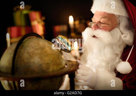 Santa Claus Blick durch die Lupe im globe Stockfoto