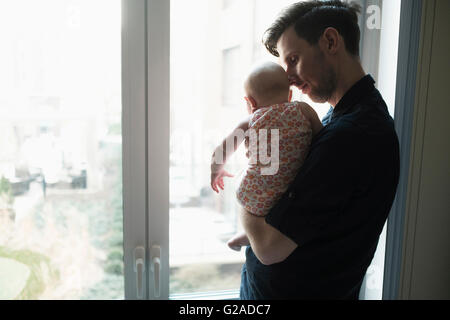 Vater Blick durch Fenster mit Tochter (2-5 Monate) Stockfoto